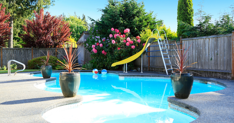 backyard pool with lush landscaping and a pool slide