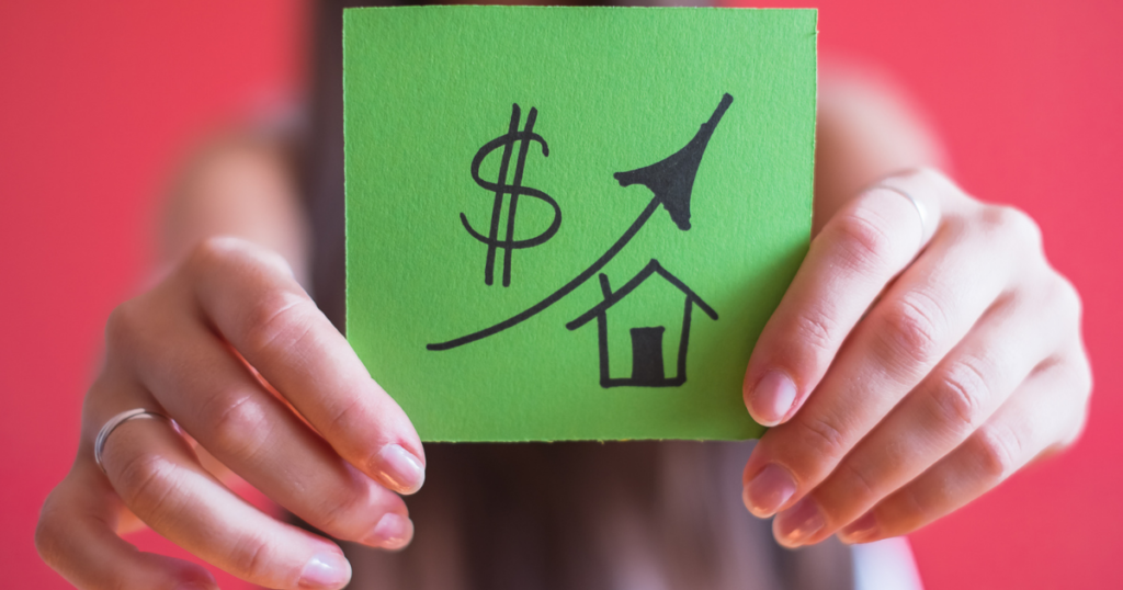 woman holding a sign with a house, dollar sign and arrow pointing up